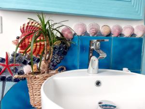 a bathroom with a sink and a basket of shells at Villa Mondello Terraces & Jacuzzi in Mondello