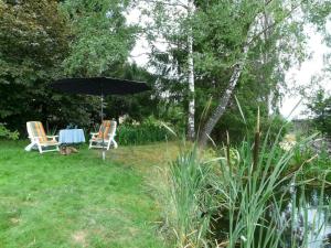 two chairs and a table with an umbrella in a yard at Ferienwohnung für 2 Personen ca 40 qm in Neureichenau, Bayern Bayerischer Wald in Neureichenau