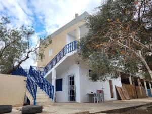 a white building with blue stairs on it at Camping Pension Zina in Zurayq Barrānīyah