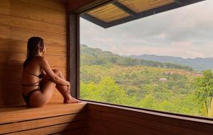 a woman sitting in a sauna looking out of a window at Sumberkima Hill Retreat in Pemuteran