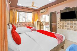 a bedroom with two beds and a tv on the wall at OYO Flagship Hotel Pakeeza in Mumbai