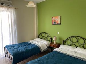 two beds in a room with green walls at Finikas in Iria