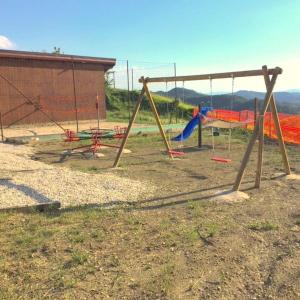 un parque infantil con columpios en un campo en Ferienwohnung für 1 Personen 3 Kinder ca 60 qm in Apecchio, Marken Provinz Pesaro-Urbino en Apecchio