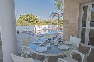 una mesa y sillas en un patio con piscina en Ferienhaus mit Privatpool für 6 Personen ca 130 qm in Pernera, Südküste von Zypern - b59089 en Protaras
