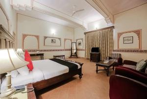 een hotelkamer met een bed en een bank bij Roop Vilas Palace in Nawalgarh