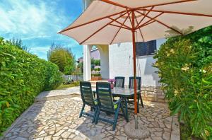 une table avec des chaises et un parasol sur une terrasse dans l'établissement Ferienwohnung für 4 Personen ca 35 qm in Fažana, Istrien Istrische Riviera, à Valbandon