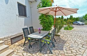 une table et des chaises avec un parasol sur une terrasse dans l'établissement Ferienwohnung für 4 Personen ca 35 qm in Fažana, Istrien Istrische Riviera, à Valbandon