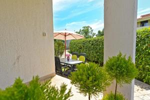 une terrasse avec une table, un parasol et des chaises dans l'établissement Ferienwohnung für 4 Personen ca 35 qm in Fažana, Istrien Istrische Riviera, à Valbandon 14 autres photos