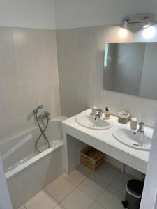 een badkamer met 2 wastafels, een bad en een spiegel bij Les marguerites in Vers Pont du Gard