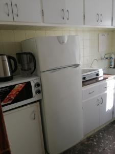 阿利坎特的住宿－Verano，厨房配有白色橱柜和白色冰箱。