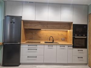a kitchen with white cabinets and a stainless steel refrigerator at K&H Tarnów Centrum in Tarnów +8 photos