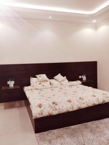 Schlafzimmer mit einem großen Bett mit einem Kopfteil aus Holz in der Unterkunft عمارة المهدية in Riad