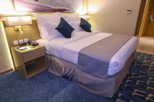 سرير أو أسرّة في غرفة في Cheerful Al Waha Hotel Unayzah - فندق شيرفل عنيزة