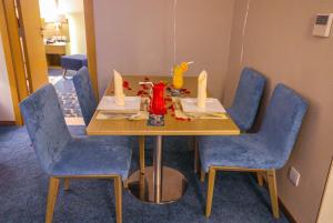 una mesa en una habitación con sillas azules y una mesa con velas en Cheerful Al Waha Hotel Unayzah - فندق شيرفل عنيزة en Unayzah