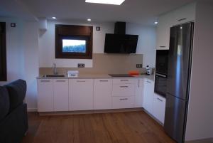 a kitchen with white cabinets and a stainless steel refrigerator at Casa los Canarios in Irijoa