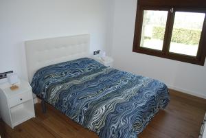 a bedroom with a bed with a blue and white blanket at Casa los Canarios in Irijoa