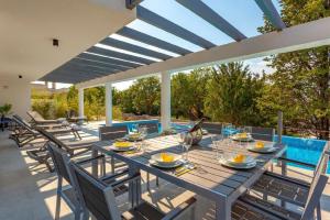 einen Essbereich im Freien mit einem Tisch, Stühlen und einem Pool in der Unterkunft Ferienhaus mit Privatpool für 8 Personen ca 234 m in Malinska, Kvarner Bucht Krk in Malinska + 14 Fotos