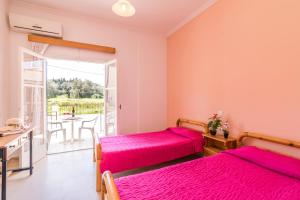 a bedroom with two beds and a table and a balcony at Nikos Apartments 1 in Kavos