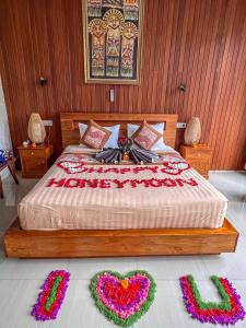 a bedroom with a bed with two heart decorations on the floor at Made Punias Jungle Paradise in Ubud