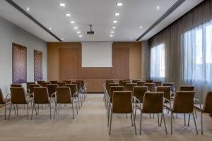 une salle de conférence avec des chaises et un écran de projection dans l'établissement AC Hotel Vicenza by Marriott, à Vicence