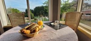 een tafel met een mand met brood en jus d'orange bij Hôtel Côté Jardin in Commercy