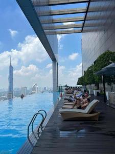 a pool with people laying on lounge chairs in the water at Vinson Suites at Platinum KLCC in Kuala Lumpur