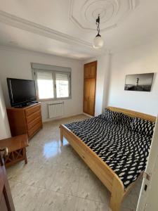 Schlafzimmer mit einem Bett und einem Flachbild-TV in der Unterkunft bel appart mosta in Mostaganem