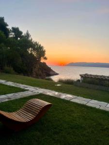a bench sitting in the grass with the sunset in the background at Agrielia Studios Katigiorgis, Agios Georgios in Agios Georgios