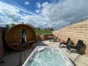 a hot tub sitting on a deck next to a building at Boven de paarden @ de Hoeveschuur in Riemst
