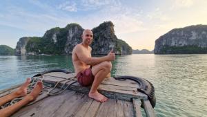 a man sitting on a boat in the water at Gia Cat Long Boutique Hotel Cat Ba in Cat Ba