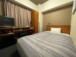 Hotel Route-Inn Asahikawa Ekimae Ichijodori في اساهيكاو: غرفه فندقيه سرير وتلفزيون