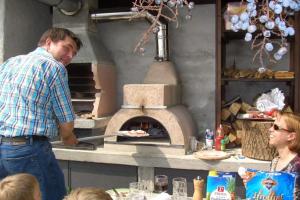 a man cooking food in an outdoor oven at Ferienwohnung für 5 Personen ca 69 qm in San Carlo, Comer See Westufer Comer See in Gravedona