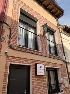 un edificio de ladrillo con dos ventanas y un cartel en él en Apartamentos Lux Carrión, en Carrión de los Condes