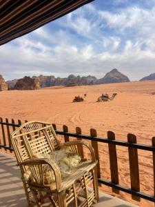 uma cadeira de vime sentada num alpendre no deserto em Wadi Rum Magic Camp em Wadi Rum