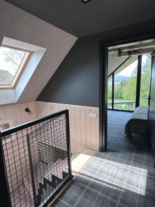 an attic room with a door with a bed and a window at U Boku Stoku in Kasina Wielka