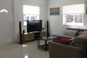 ein Wohnzimmer mit einem Sofa und einem Flachbild-TV in der Unterkunft Sunset Villa private complex heated pool in Ayia Napa
