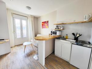 a kitchen with white cabinets and a wooden counter top at Allen - 2min de la plage du sillon et intra in Saint Malo