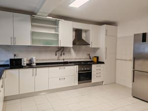 uma cozinha com armários brancos e electrodomésticos de aço inoxidável em Villa dos castanheiros em Cascais