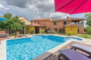 a pool in front of a house with an umbrella at Ferienhaus mit Privatpool für 6 Personen ca 140 qm in Svetvincenat, Istrien Binnenland von Istrien in Pula