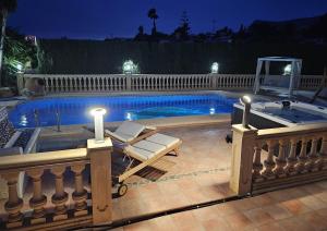 a swimming pool with two lounge chairs next to it at night at Luxury Villa - pool, hot tub, aircon, TVs, home cinema, office, Gbit Internet, sports equipment in Calpe