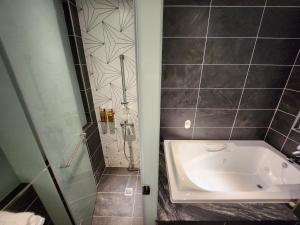 La salle de bains est pourvue d'une baignoire et d'une douche. dans l'établissement Bentley Hotel, à Zhongli