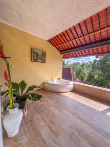 a bathroom with a tub and a large window at Made Punias Jungle Paradise in Ubud