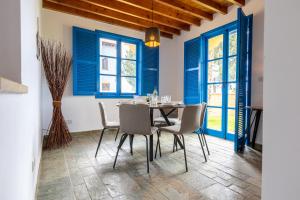 ein Esszimmer mit blauen Fenstern sowie einem Tisch und Stühlen in der Unterkunft The Olympians Villas in Polis Chrysochous