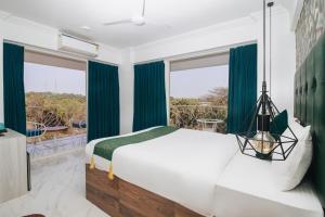 a bedroom with a large bed and green curtains at The Mayfield Resort, Vagator in Anjuna