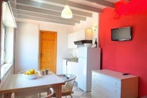 Il comprend une cuisine dotée d'un mur rouge, d'une table et d'un réfrigérateur. dans l'établissement Ferienwohnung für 6 Personen ca 50 qm in Giardini Naxos, Sizilien Ostküste von Sizilien, à Giardini Naxos