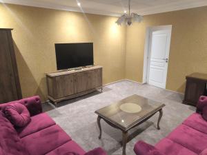 sala de estar con muebles de color púrpura y TV de pantalla plana. en ApartmanyHurbanova1, en Bardejov