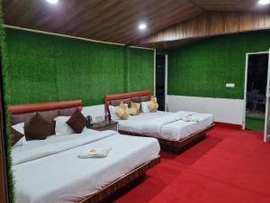 two beds in a room with green walls at Cascade Resort And Cottages in Mussoorie