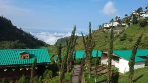 a building with a green roof on a hill at Cascade Resort And Cottages in Mussoorie