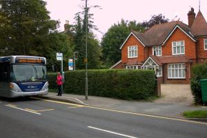 a woman is waiting for a bus at a bus stop at Gatwick Turret Guest House in Horley