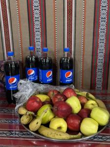 um prato de maçãs e bananas e dois frascos de refrigerante em Wadi Rum Magic Camp em Wadi Rum